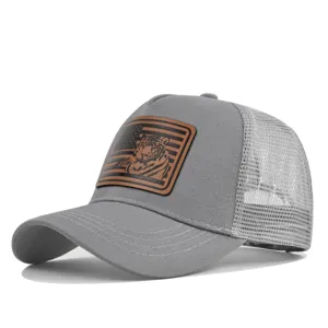 Nahaufnahme der grauen Mesh-Trucker-Mütze mit braunem Tiger-Lederaufnäher vorne.