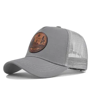 Primer plano detallado de la gorra trucker gris de malla con un parche de cuero marrón.