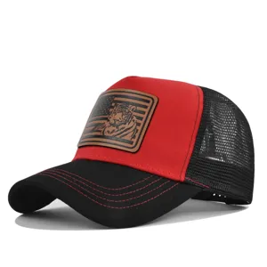 Nahansicht der rot-schwarzen Trucker-Cap mit stilvollem Tiger-Lederaufnäher Detail.