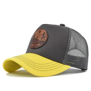 Gorra de camionero gris y amarilla con malla trasera y parche de cuero elegante.