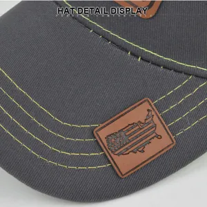 Detailed view of grey baseball cap brim with yellow stitching and US map leather patch.