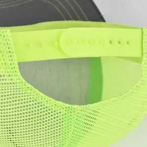 Close-up detail of neon green mesh trucker hat snapback strap and breathable fabric.