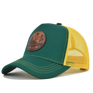 Vista detallada de gorra trucker verde y amarilla con parche de cuero y visera curvada.