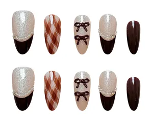 Set de uñas postizas con efecto ojo de gato, cuadros marrones, lazos 3D, perlas y estrás.