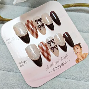 Uñas postizas hechas a mano con cuadros marrones, ojo de gato, perlas y bonitos lazos.