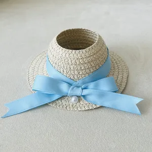 Detail view of the woven doll straw hat featuring a delicate light blue bow and pearl accent.