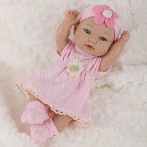 Close-up of 11-inch reborn baby doll in pink knitted dress and floral headband on soft fur.