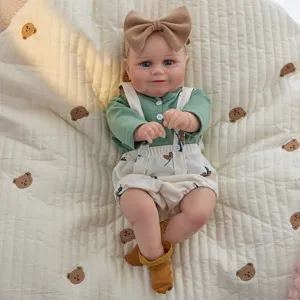 Gros plan détaillé d'une jolie poupée bébé reborn de 20 pouces avec haut vert et bandeau.