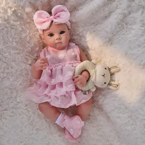 Detailed view of 45cm reborn baby doll with pink dress, bow headband, and plush rabbit toy.