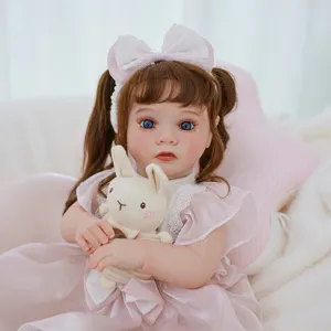 Gros plan d'une jolie poupée reborn avec des yeux bleus, des queues de cheval et une robe rose.
