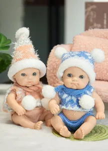 Close-up view of cute 8-inch reborn vinyl baby dolls wearing cozy winter hats and knitted scarves.