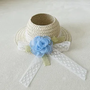 Close-up detail of a handmade woven doll straw hat with blue chiffon flower and white lace ribbons.