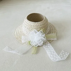Detailed shot of doll straw hat accessory with white lace and flower, cute woven sun hat.
