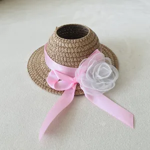 Detailed shot of a woven doll straw hat with pink ribbon and flower, perfect doll accessory.