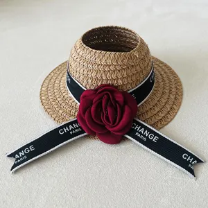 Miniature doll straw hat with red camellia flower and ribbon, perfect fashion accessory.