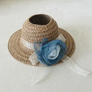 Miniature woven straw hat with blue and white organza flower decoration for doll accessories.