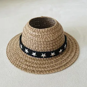 Detailed view of miniature straw hat for dolls, featuring black band and silver star studs.