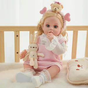 Close-up detail of a cute reborn baby doll wearing pink knit dress and cute bear headband.