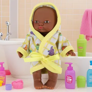 Primer plano detallado del muñeco bebé negro con albornoz con capucha amarilla y set de baño.