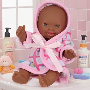 Primer plano detallado de una adorable muñeca bebé africana con albornoz a cuadros rosas.