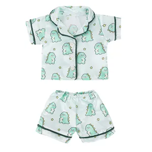 Cute dinosaur print doll pajama set detail, featuring soft light green fabric and green trim.