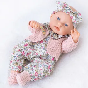 Primo piano dettagliato della bambola reborn da 30 cm con cardigan rosa e tutina floreale.