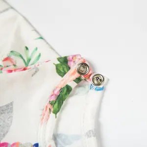 Nahaufnahme des Puppenkleidstoffes mit Blumenmuster und praktischen Metalldruckknöpfen.