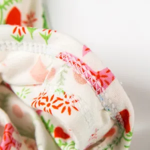 Close-up detail shot of doll clothing fabric stitching, neat hem and floral botanical print.