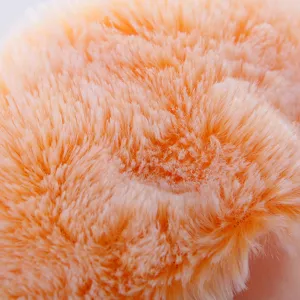 Close-up detail of soft orange plush fabric, fluffy texture for doll clothing accessories.