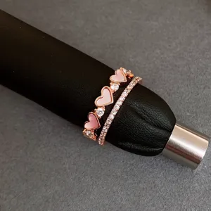 Close-up of a double-layer rose gold ring with pink heart charms and sparkling zirconia stones.
