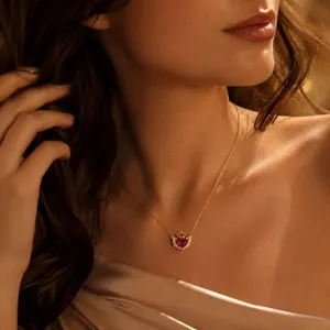 Close-up detail view of a gold-plated crown heart pendant necklace with red crystal gemstone.