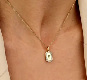 Gedetailleerde close-up van een delicate rechthoekige initialen ketting met schitterende zirkonia.