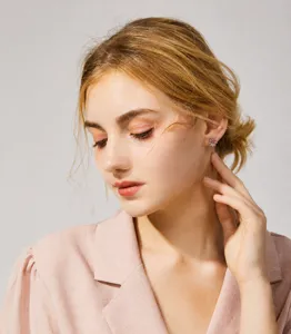 Detailed close-up of delicate stud earrings worn by a model in pink blazer, elegant style.
