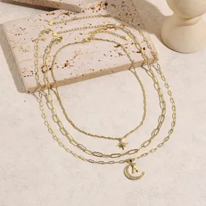 Detailed shot of multi-layer gold tone layered necklace with star moon and letter pendants.
