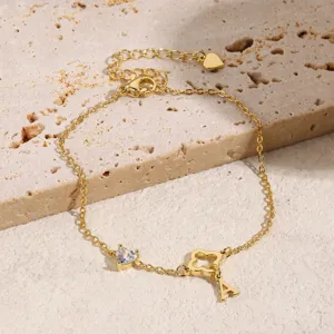 Elegantes vergoldetes Armband mit ausgehöhltem Kleeblatt, Kristallherz und Buchstabenanhänger.