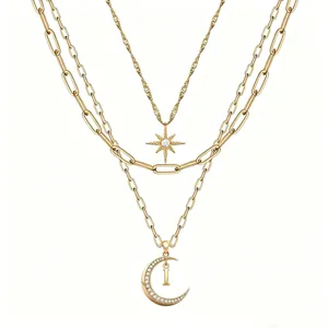 Gold layered necklace detail showing star, diamond crescent moon and letter I pendants.
