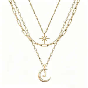 Gold layered necklace detail with paperclip chain, crystal star and letter J moon pendant.