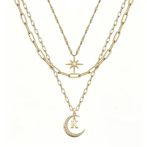 Layered gold necklace featuring star and moon pendants with crystal accents and initial letter K.