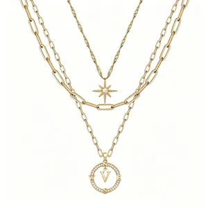 Primo piano della collana multistrato dorata con ciondolo a stella e lettera bussola.