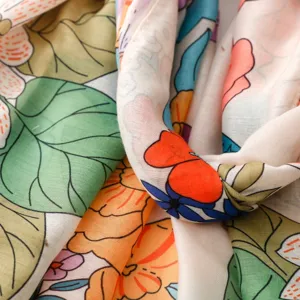 Gros plan detail de tissu foulard imprime floral retro colore, texture douce, motif vif.