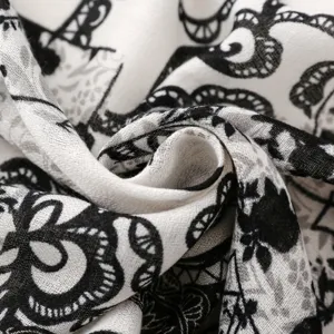 Close-up detail of the black and white floral printed scarf, showing soft fabric and retro pattern.