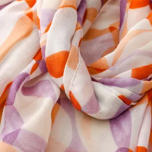 Nahaufnahme von Stoff mit abstraktem Kieselsteinmuster, weiche Textur in orange und lila.
