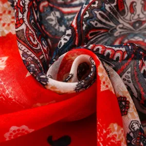 Nahaufnahme eines boho-Schals mit rot-blauem Paisleymuster und weicher Stofftextur.