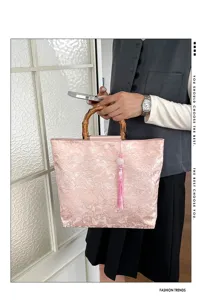 Detail de sac a main en tissu jacquard rose, elegante poignee bambou et beau pompon.
