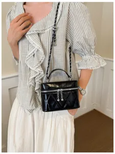 Primer plano detallado del elegante bolso de hombro acolchado negro con cadena y cremallera.
