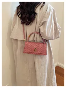 Pink woven shoulder bag, detailed view of elegant crossbody handbag with metal lock.