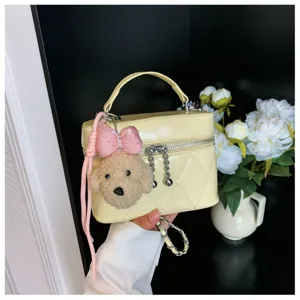 Vista detallada del bolso acolchado amarillo con colgante de perro de peluche y cadena.