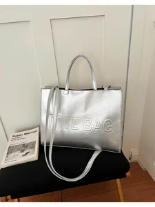 Detalle de bolso tote plateado metálico con diseño grabado y textura elegante y moderna.