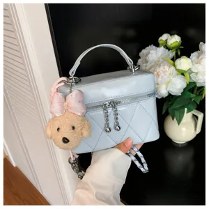 Bolso de mano acolchado en azul claro con cadena y detalle de perrito de peluche.