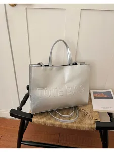 Bolso tote shopper metálico plateado con diseño de letras en relieve para uso diario.